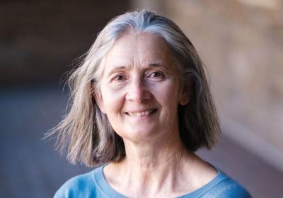 Kathy Tierney stands with arms crossed, smiling, wearing a blue shirt